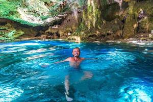 Tourist guide blue turquoise water limestone cave sinkhole cenote Mexico. photo