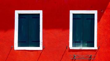 two windows with white frame on red color wall photo