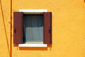 ventana marrón en burano en la pared de color naranja foto