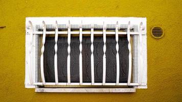 Window on yellow mustard wall building in Burano photo