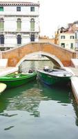 puente y barcos en canal en venecia, italia foto