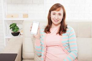 Blank white space on smartphone screen.Woman holding mobile phone. Smiling Attractive middle age woman with cell phone. Mock up and copy space for advertising. photo