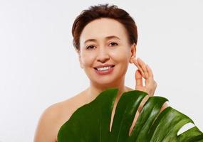 Beauty middle age woman macro face portrait. Spa and anti aging concept and leaf Isolated on white background. Plastic surgery and collagen face injections.Wrinkles and menopause. Mock up. Copy space. photo