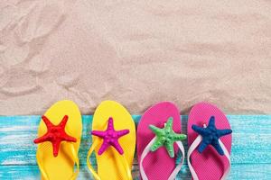Sand copy space. Sand background top view. Multicolored starfish on beach flip flops photo