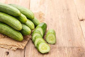 Pile and slice cucumber on wooden table background. Food and healthcare concept photo