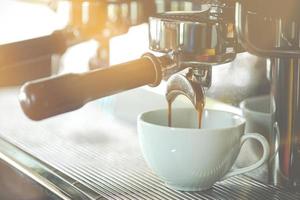 Coffee extraction from coffee machine to white cup in coffee shop. Food and beverage concept photo