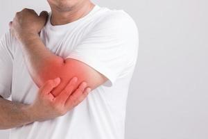 Close up man holding on elbow and feeling a pain. Studio shot isolated on grey background with copy space for text photo