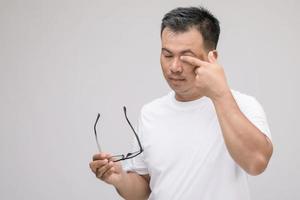 Eye irritation concept, Portrait of Asian man in posture of eye tired,  irritation or problem about his eye. Studio shot isolated on grey photo