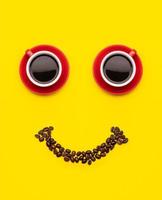 Cup of coffee and coffee beans with smile face concept, Top view on yellow background. For morning happy concept photo