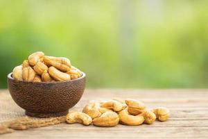 Pile of roasted cashew nut in bowl on the table. Blur green background photo