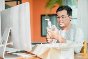 Man holding and looking to hand sanitizer gel bottle that he ordered to use at home, Work from home and Healthy concept photo