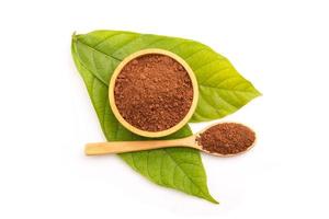 Pile of Cocoa powder in wooden spoon and green leaf  isolated on white background photo