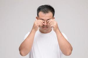 concepto de irritación ocular, retrato de un hombre asiático en postura de ojo cansado, irritación o problema con su ojo. tiro del estudio aislado en gris foto