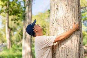 Asian man giving a hug on big teak tree hug. Love tree and nature or environment concept photo