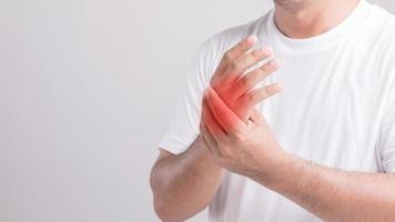 Close up man touching palm and feeling a pain. Studio shot isolated on grey background with copy space for text photo