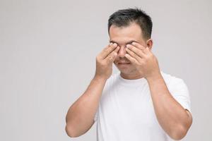 concepto de irritación ocular, retrato de un hombre asiático en postura de ojo cansado, irritación o problema con su ojo. tiro del estudio aislado en gris foto