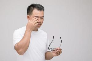 concepto de irritación ocular, retrato de un hombre asiático en postura de ojo cansado, irritación o problema con su ojo. tiro del estudio aislado en gris foto