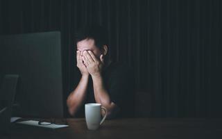 Eyestrain concept. Man touching his eyes because tired after working long time on computer photo