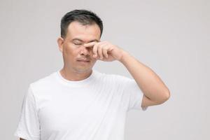 concepto de irritación ocular, retrato de un hombre asiático en postura de ojo cansado, irritación o problema con su ojo. tiro del estudio aislado en gris foto