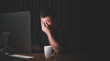 Eyestrain concept. Man touching his eyes because tired after working long time on computer photo