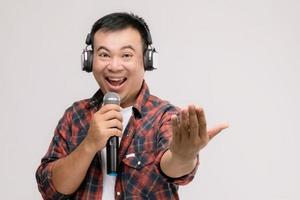 retrato de un hombre asiático escuchando una canción o música desde un auricular negro. tiro del estudio aislado en gris foto