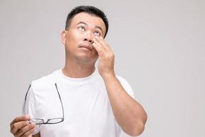 concepto de irritación ocular, retrato de un hombre asiático en postura de ojo cansado, irritación o problema con su ojo. tiro del estudio aislado en gris foto