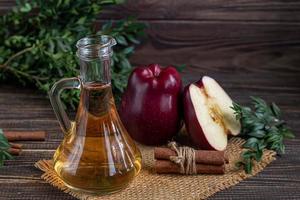 Apple cider vinegar and red apples on a dark, wooden background. Selective focus. fermented product. Healthy food. photo