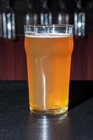 Glasses with different types of craft beer on a wooden bar. In glasses and bottles. Nuts and crackers on the table. On a dark background. photo