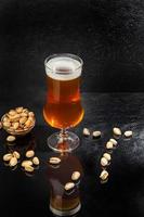 Glasses with different types of craft beer on a wooden bar. In glasses and bottles. Nuts and crackers on the table. On a dark background. photo