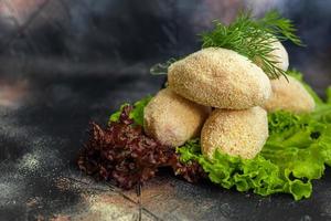 Semi-finished cutlets with breaded cheese or butter. Fast food preparation. On a dark background. photo