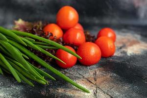 Fresh vegetables for salad. Tomatoes and lettuce, cucumbers with zucchini and cabbage with dill. Spring harvest, benefits and vitamins. On a dark background. photo