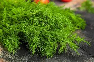 Fresh vegetables for salad. Tomatoes and lettuce, cucumbers with zucchini and cabbage with dill. Spring harvest, benefits and vitamins. On a dark background. photo