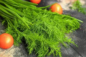 Fresh vegetables for salad. Tomatoes and lettuce, cucumbers with zucchini and cabbage with dill. Spring harvest, benefits and vitamins. On a dark background. photo