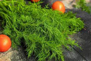 Fresh vegetables for salad. Tomatoes and lettuce, cucumbers with zucchini and cabbage with dill. Spring harvest, benefits and vitamins. On a dark background. photo