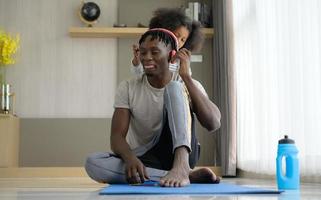 Asian-African American father and son relaxing and listening to music together after yoga exercise in the living room of the house. photo
