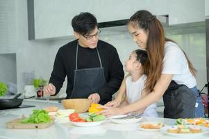 Asian family They are having cooking together happily in the kitchen room of the house. photo