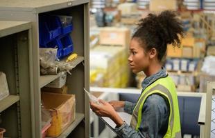 Female warehouse worker Counting items in an industrial warehouse on the factory's mezzanine floor. which is a storage for small and light electronic parts. photo