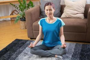 mujer practicando yoga en casa desde clases en línea después del trabajo. alivio del estrés, relajación muscular, ejercicios de respiración, ejercicio, meditación. foto