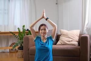 aliviar el estrés, relajar los músculos, practicar la respiración, el ejercicio, la meditación. mujer practicando yoga y músculos en casa de vacaciones. foto