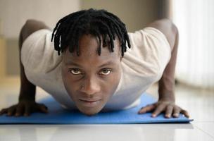 Young African man doing yoga exercise in the living room of his homewith the pleasure of relaxing with light sports In the morning atmosphere of the day. photo