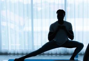 Young African man doing yoga exercise in the living room of his homewith the pleasure of relaxing with light sports In the morning atmosphere of the day. photo