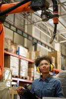 A young female worker is controlling a mechanical robot. to sort out the items that come into the warehouse to wait for the next shipment. photo