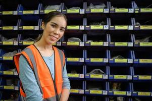 Female warehouse worker Counting small parts stored in the blue storage compartment. to check the remaining amount in order to prepare for the next order photo