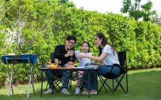 las actividades de vacaciones familiares incluyen padre, madre e hijos con barbacoa para acampar y jugar juntos en el patio felizmente de vacaciones.