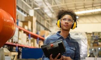 A young female worker is controlling a mechanical robot. to sort out the items that come into the warehouse to wait for the next shipment. photo