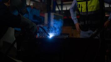 soldador trabajando metal de soldadura con ingeniero para controlar de cerca el trabajo a fin de obtener la calidad de acuerdo con la forma prescrita. foto