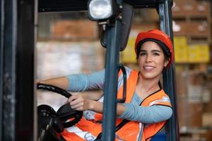 retrato de una mujer asiática con un montacargas usado para levantar objetos pesados en un almacén. foto