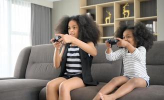 dos hermanos de una familia asiático-afroamericana. relajarse y jugar juegos en línea en la sala de estar de la casa. foto