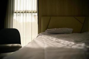 A bedroom showing the golden morning sun shining through the curtains through the window into the room photo