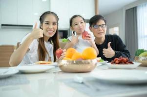 familia asiática están desayunando juntos felizmente en el comedor de la casa. foto